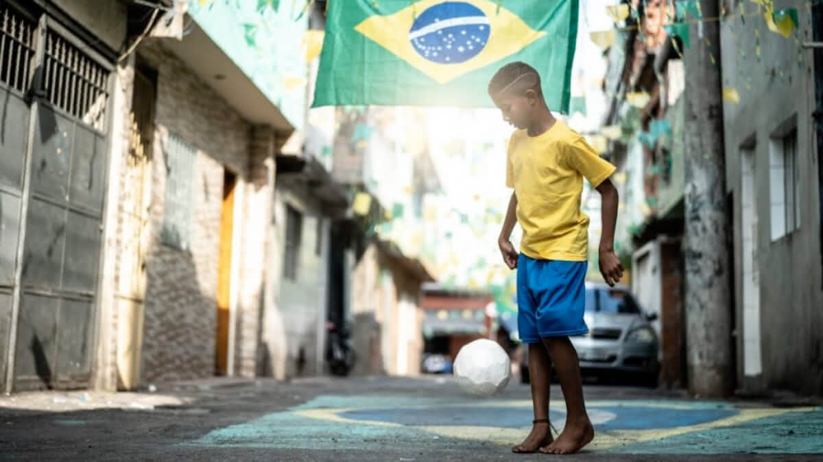 garoto jogando futebol na favela